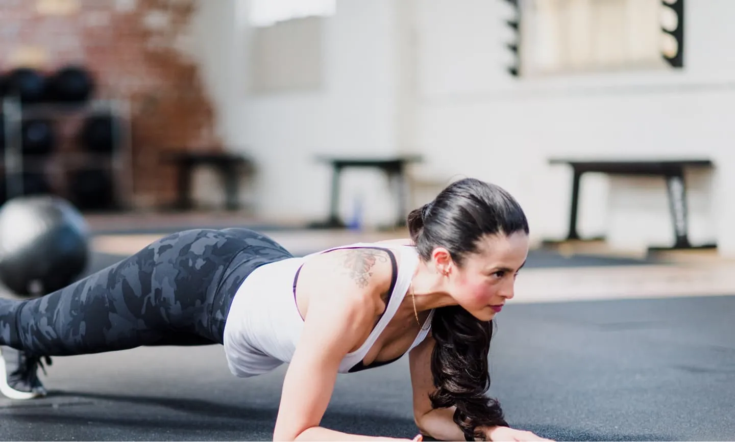 A Title 29 Fitness member holding a plank during a HIIT class in Fresno